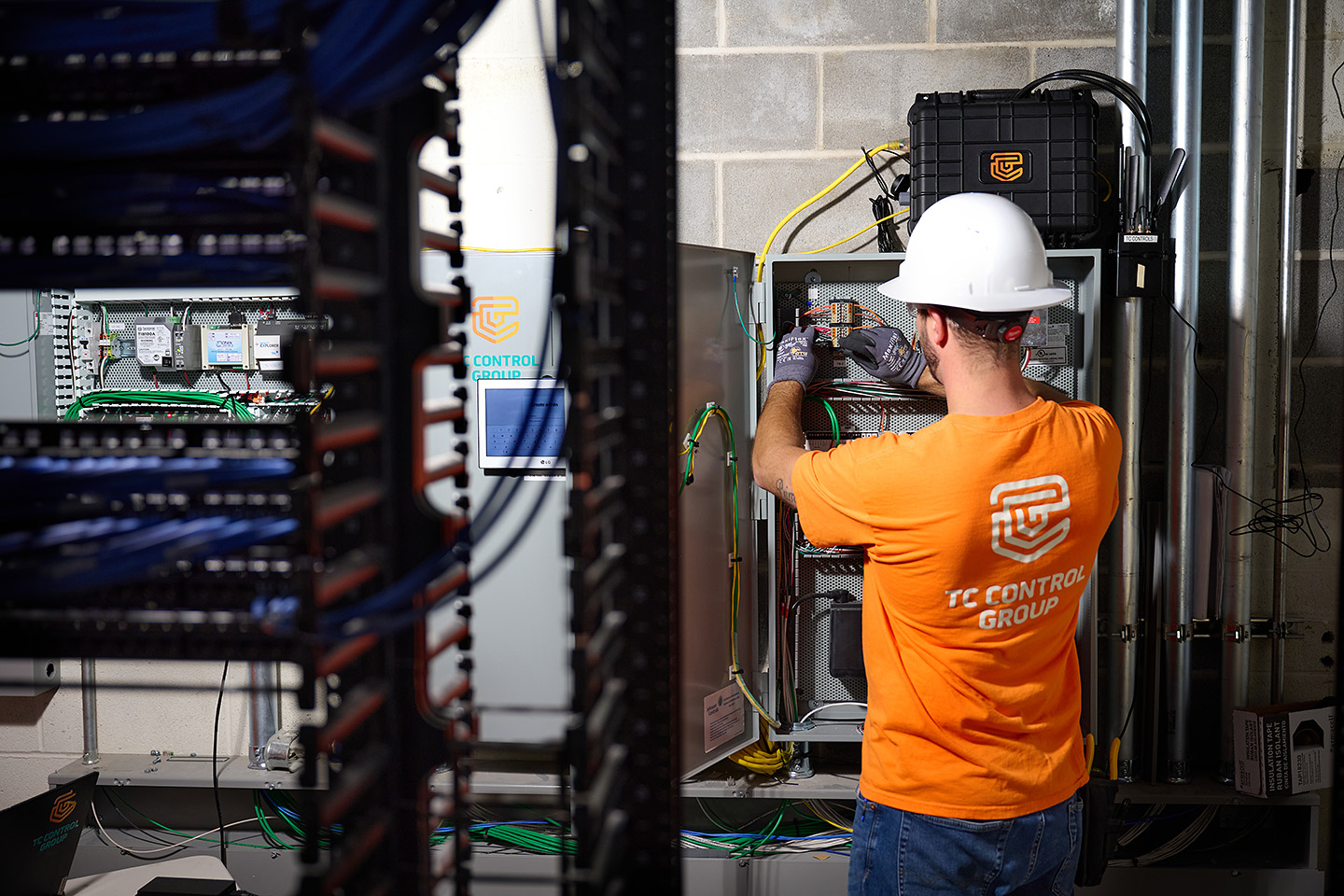TC Controls technician terminating wiring inside an open BMS control panel in the Cambridge office building's server room