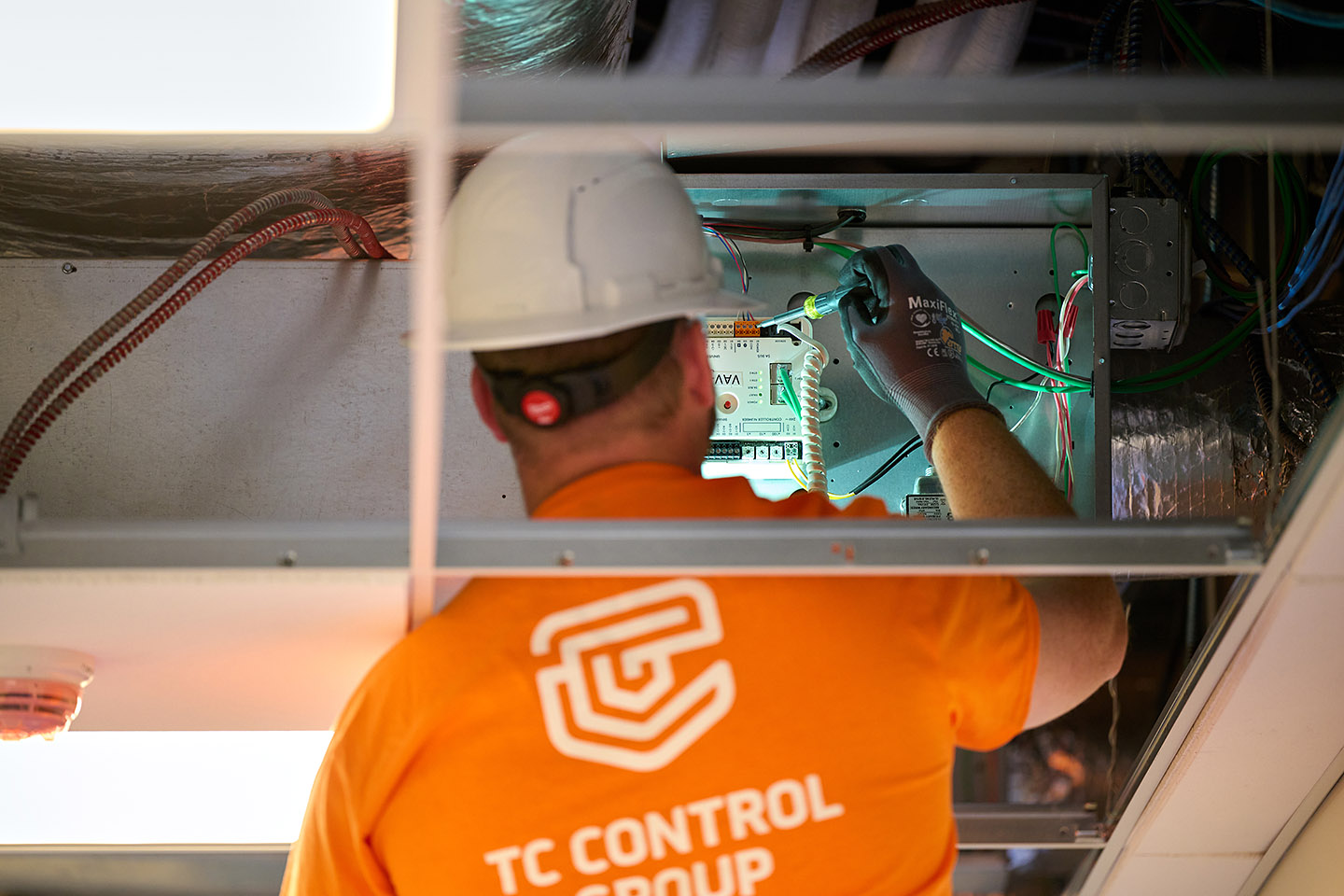 TC Controls technician installing a VAV controller in an above-ceiling plenum