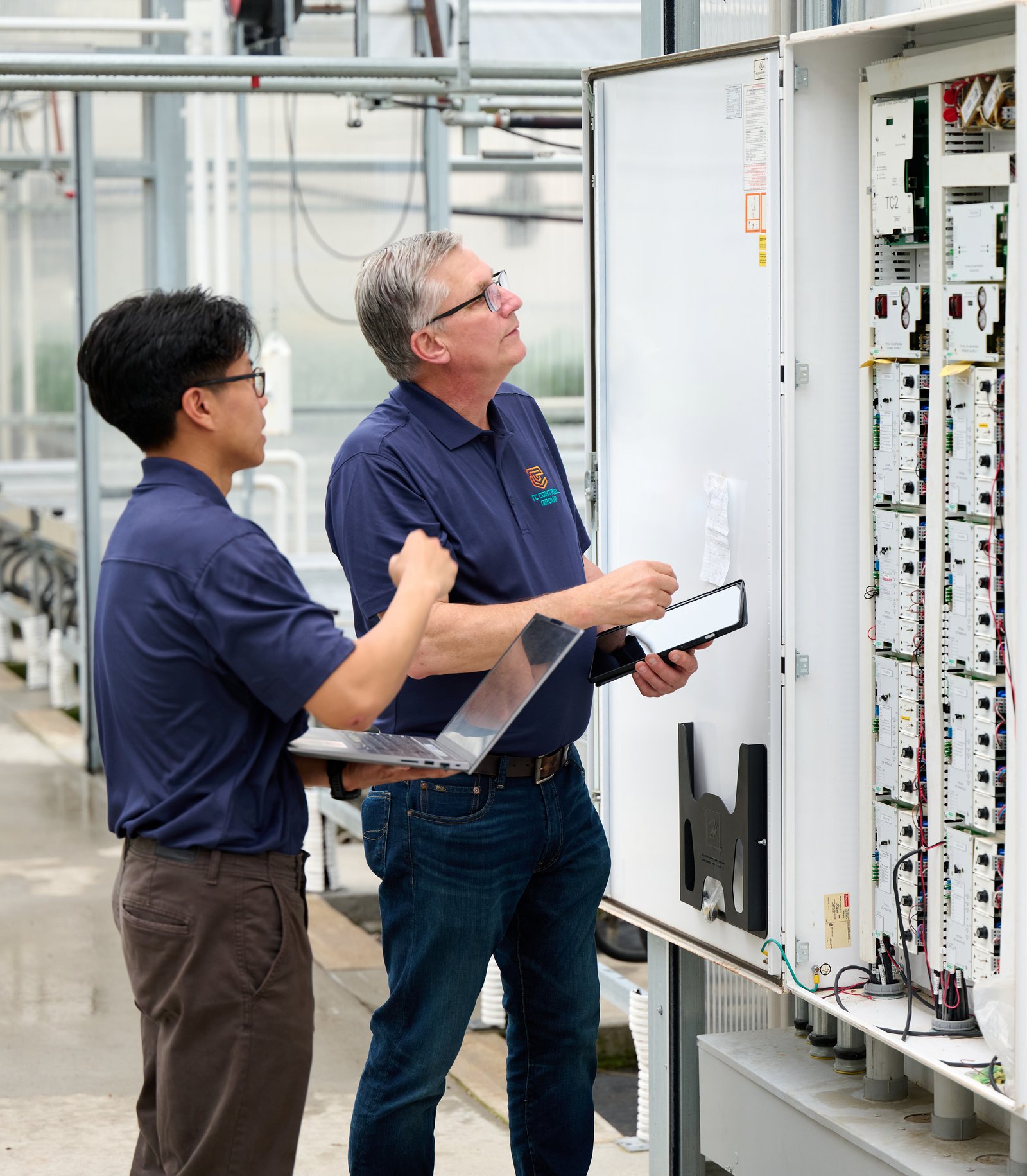 TC Controls technicians programming a climate control panel inside a commercial greenhouse
